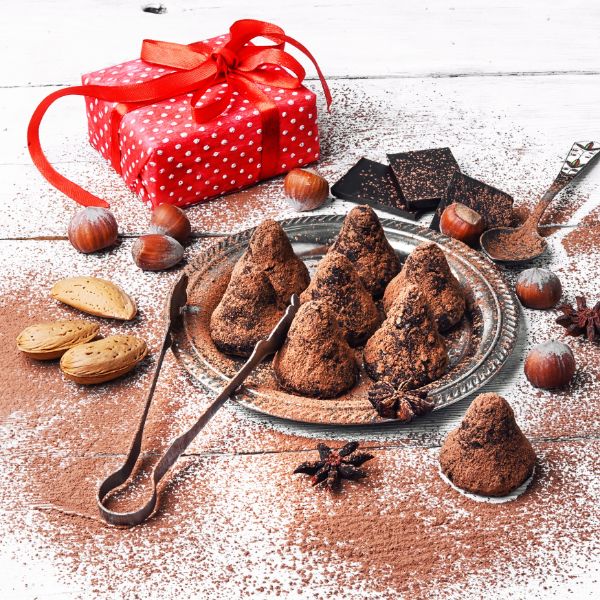 A chocolate truffles in a dessert dish with tongs and a red gift box