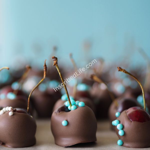 Chocolate-covered Cherries with light blue sprinkles against a light blue background