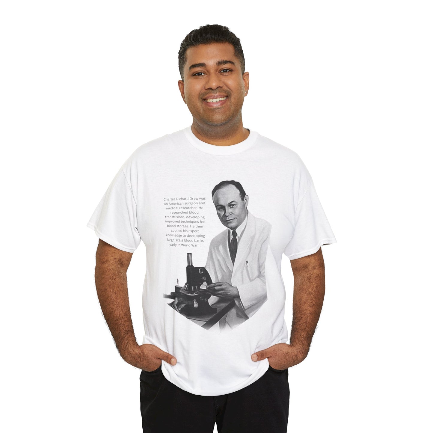 A young man standing with his hands in pockets, smiling, and wearing the Dr. Charles Drew Tribute T-shirt in white 