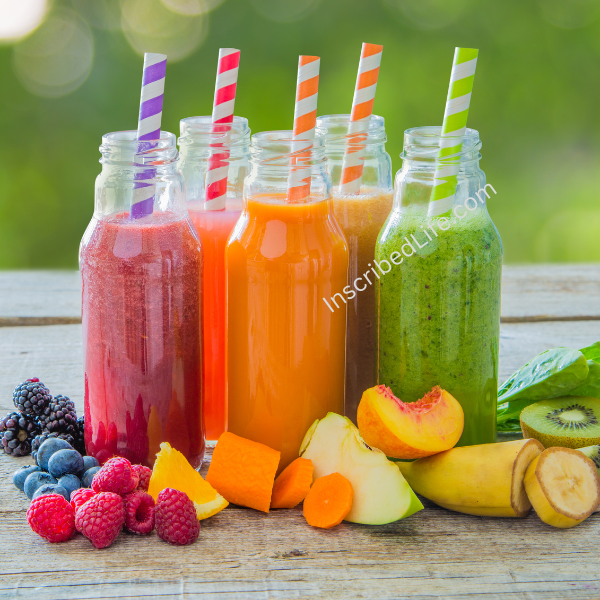 A group of fruit smoothies with straws and fruits in front