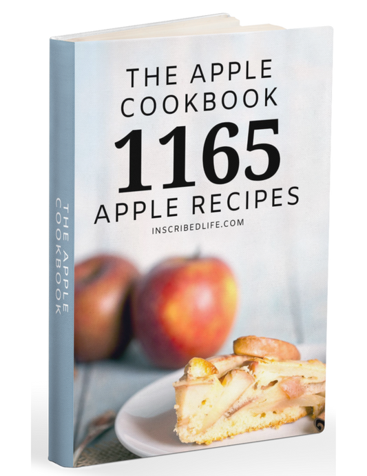 The Apple Cookbook standing with two apples behind a slice of apple pie on a dessert plate